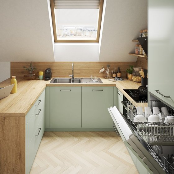 Cocina moderna bajo techo inclinado con muebles verde pastel, encimera de madera,